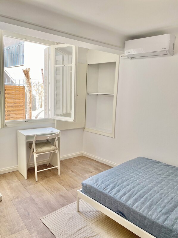 A bedroom with a bed, a desk, and a window.