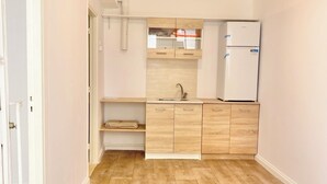 Una cocina compacta con armarios de madera, un lavamanos empotrado y un refrigerador.