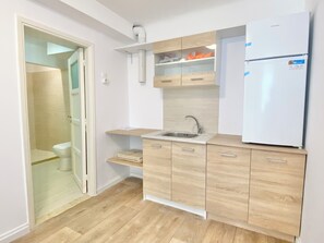 A compact kitchen with a sink, wooden cabinets, and a white refrigerator. - Quiet Flat With Outdoor Space in Central Athens (Athens)