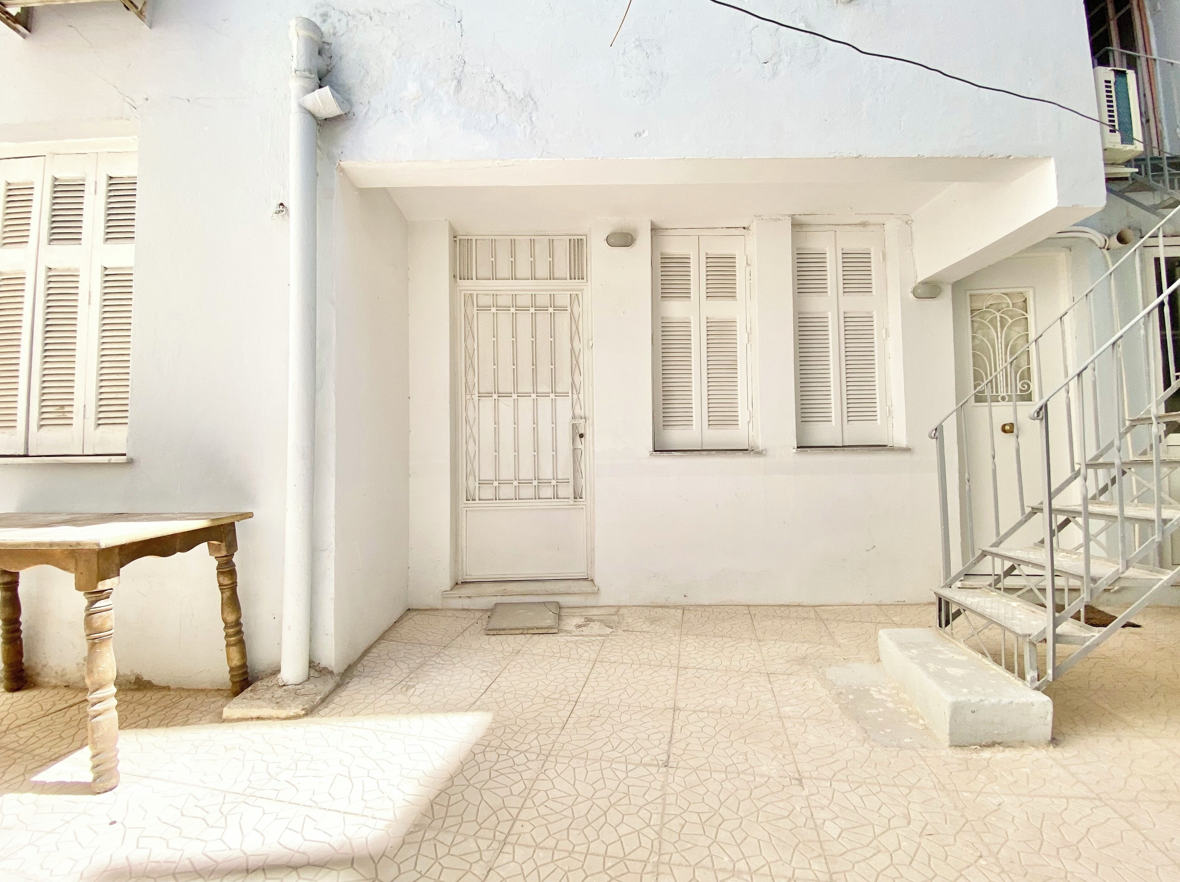 A white building with a tiled floor, a wooden table, and a staircase.