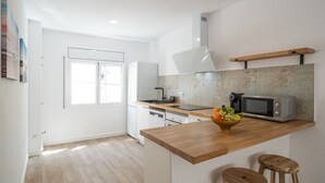 Una cocina moderna con armarios blancos, encimera de madera, microondas y un lavamanos.