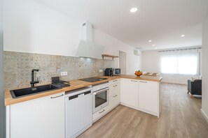 Una cocina moderna con armarios blancos, encimera de granito, horno empotrado y pileta negra.