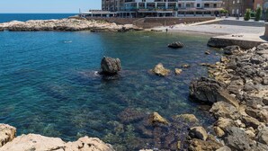Un hotel frente al mar con aguas cristalinas, costa rocosa y vistas al océano.
