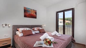 Een slaapkamer met een bed, kussens, een tijdschrift en een bloemenboeket.