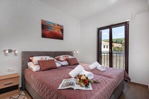 Een slaapkamer met een bed, kussens, een tijdschrift en een bloemenboeket.