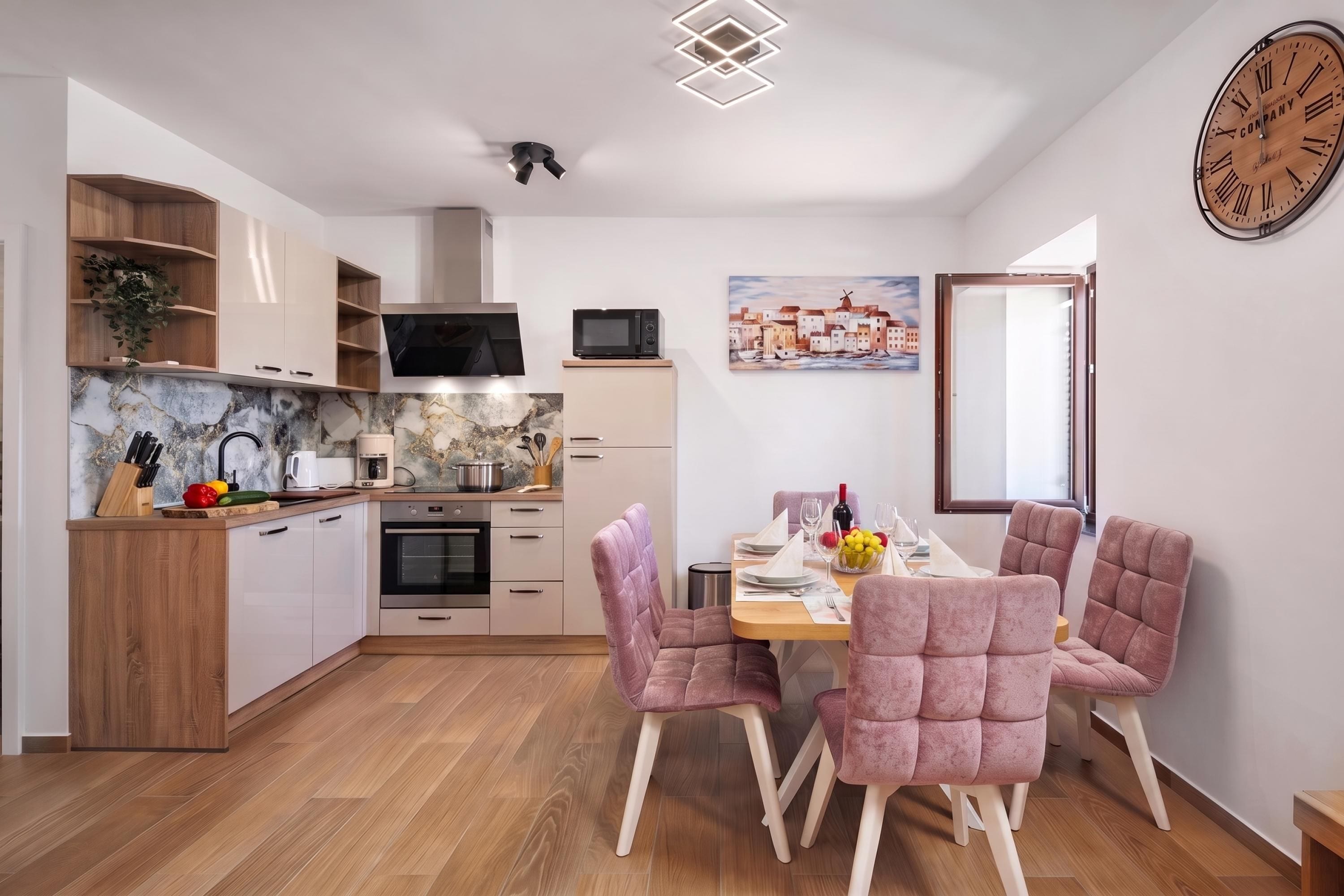 Una cocina moderna con armarios de madera, un microondas y un comedor con sillas tapizadas en rosa.