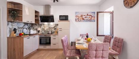 Una cocina moderna con armarios de madera, un microondas y un comedor con sillas tapizadas en rosa.