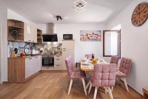 Una cocina moderna con armarios de madera, un microondas y un comedor con sillas tapizadas en rosa.