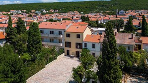 A residential area with red-tiled roofs, a mix of single and multi-story buildings, and surrounding greenery. - Seafront Apartment Nana 2 (Punat)
