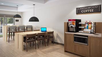 A modern coffee shop interior with a wooden counter, a coffee machine, a laptop on a table, and a sign that reads "CANDLEWOOD COFFEE".