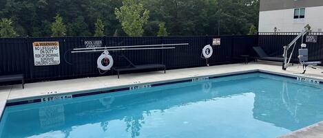 Un espace piscine équipé d’un poste de surveillance pour sauveteur, d’un dispositif d’élévation pour faciliter l’accès à la piscine et d’un panneau indiquant qu’il est interdit de plonger.