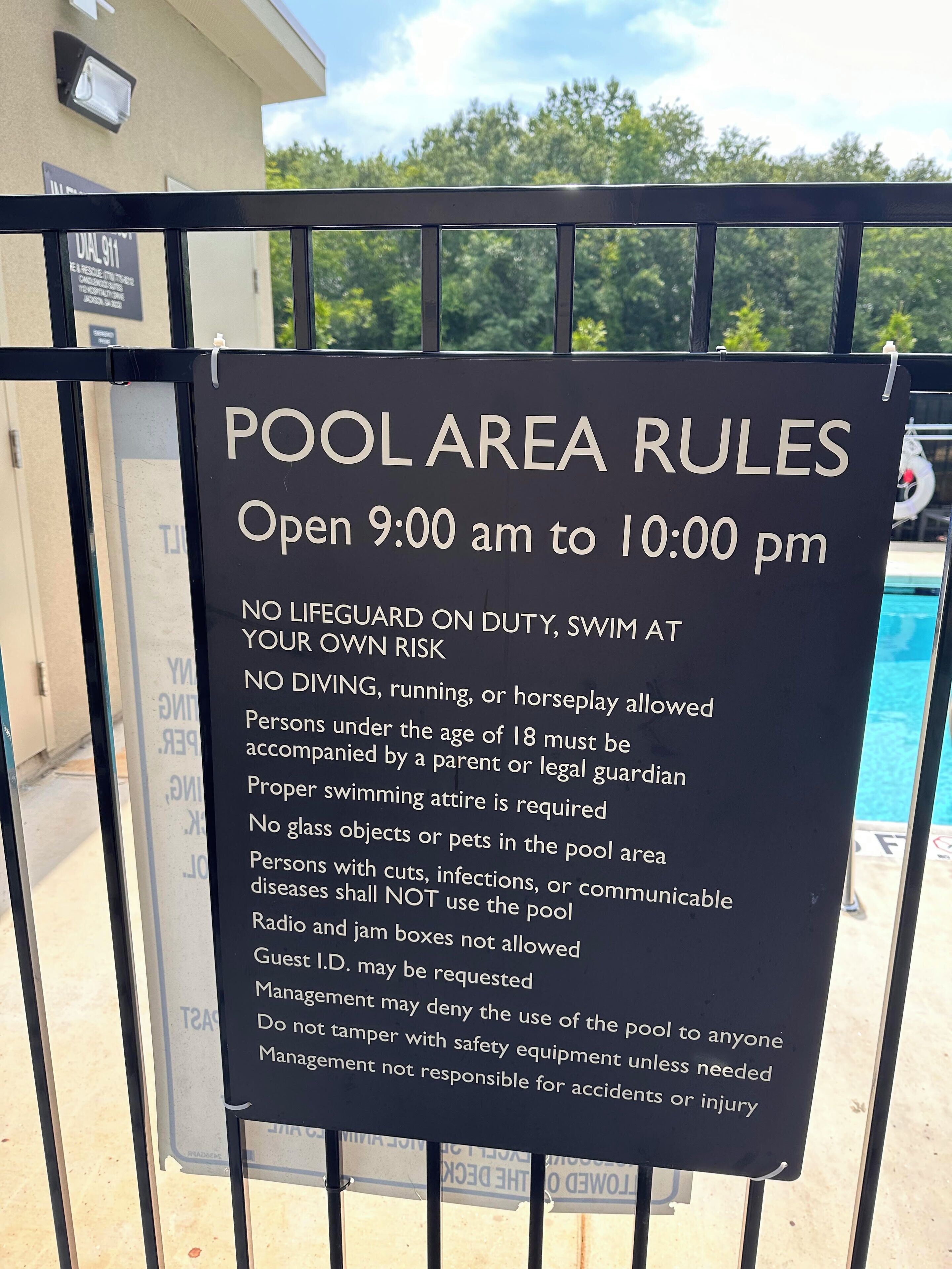 Cartel con las normas del área de la piscina, incluyendo horarios de funcionamiento y restricciones.