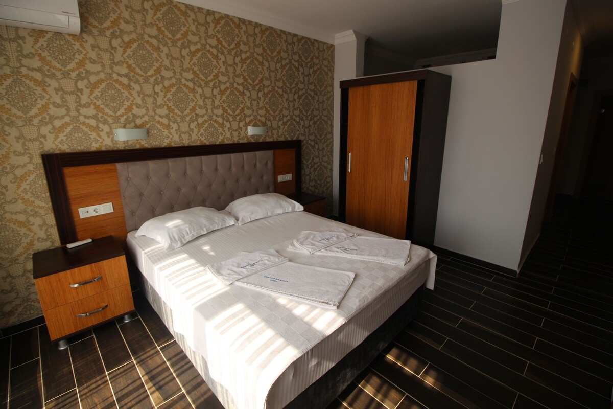 A hotel room with a bed, a nightstand, a wardrobe, and a patterned wall.