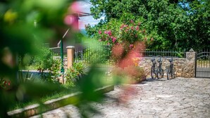 A stone pathway leading to a gated area with bicycles parked. - Villa Giovanna (Rakalj)