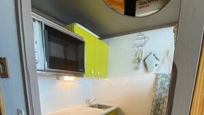 Una cocina compacta con microondas, lavaplatos y escurreplatos.