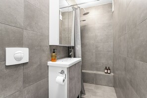 A modern bathroom with a shower, a sink, and a toilet. - Reykjavík Central Guesthouse (Reykjavik)