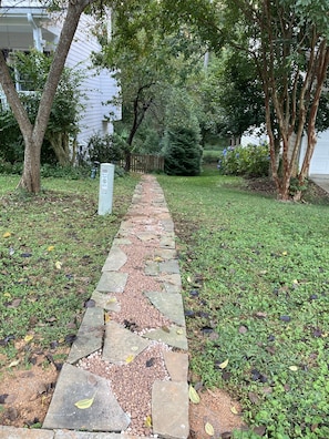 A stone pathway leading to a house with a mailbox and a wooden fence in the background. - Carolina Hideaway – Spacious 2BR Apartment with King Bed & Fenced Yard, Near UNC (Chapel Hill)