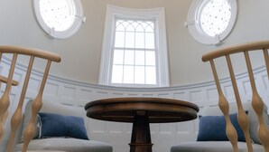 A room with a round wooden table, two wooden chairs, a large window, and a ceiling light fixture. - The Bell Inn (Peabody)