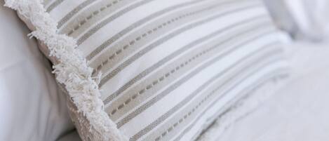 A bed with white bedding and a striped pillow.