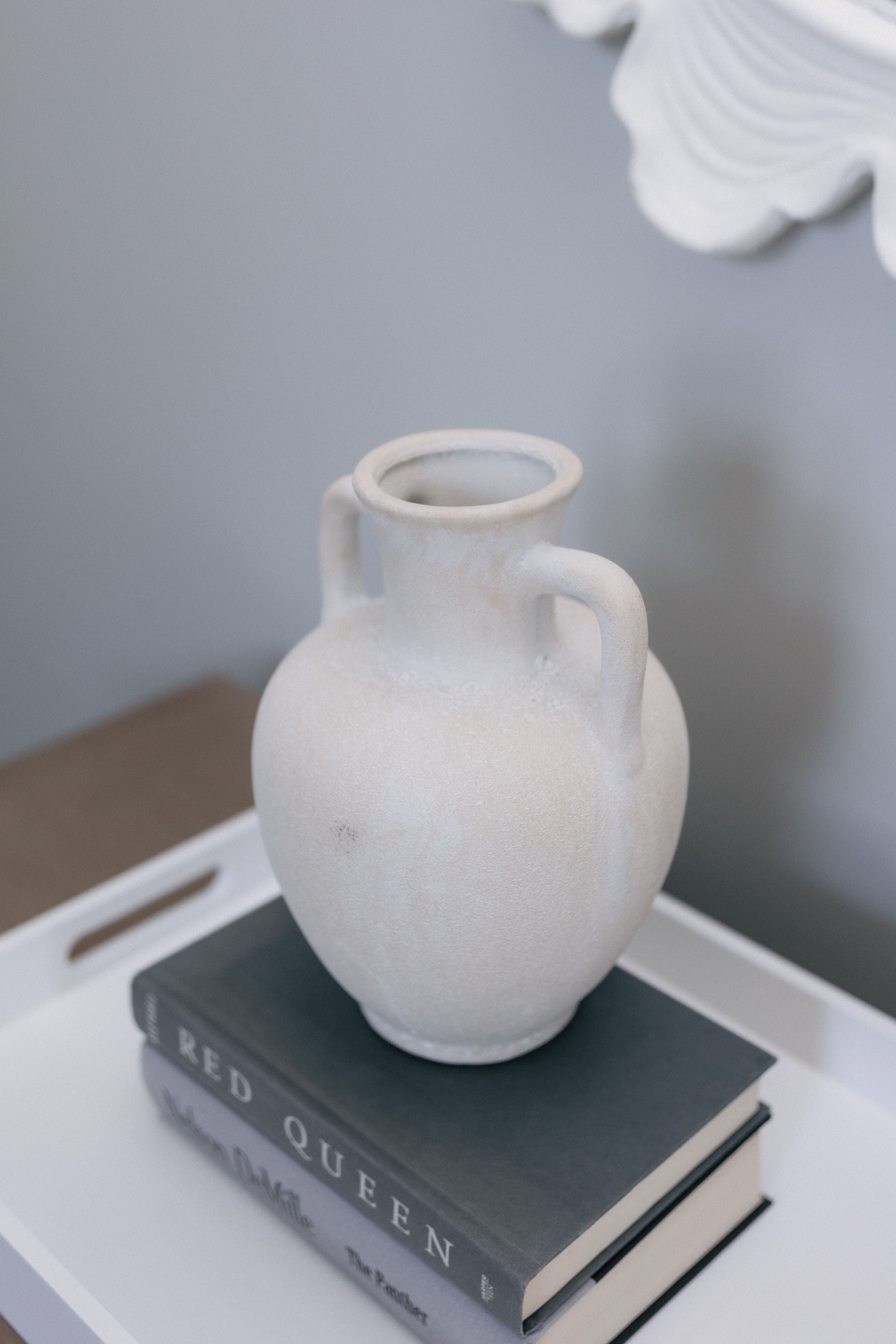 Un pichet en céramique blanche posé sur une pile de livres.
