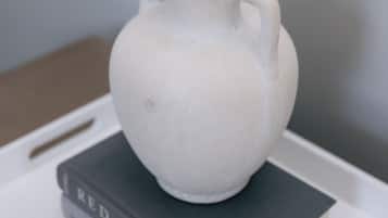 Un pichet en céramique blanche posé sur une pile de livres.