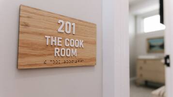 Una señal de madera con el texto "201 THE COOK ROOM" en una pared.