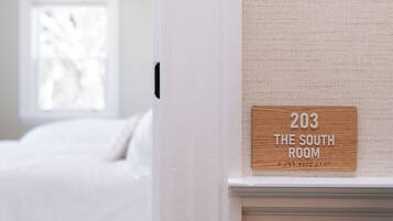 A sign indicating room number 203, labeled as "The South Room," mounted on a textured wall near a window.