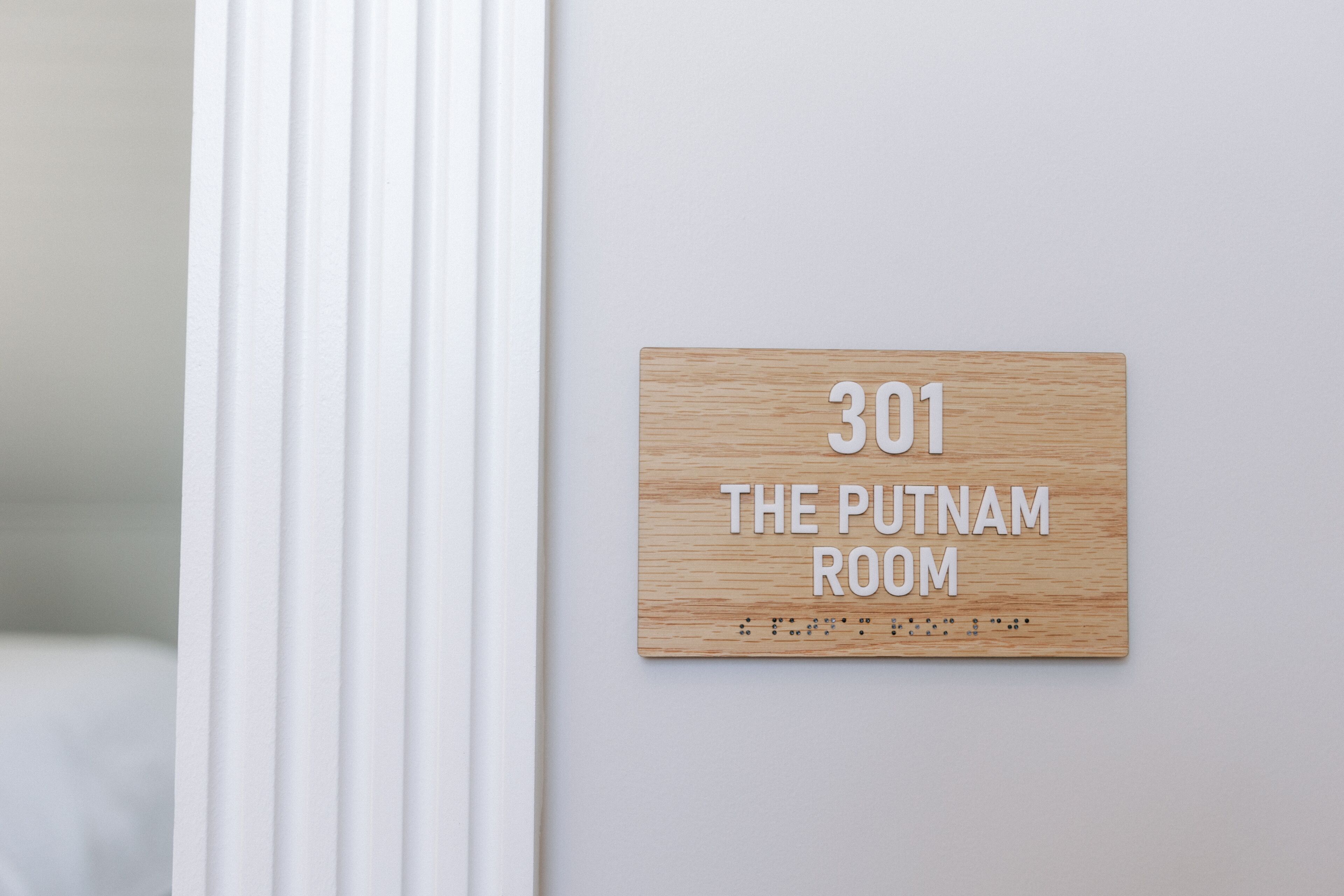 A wooden sign with the number 301 and the text 'The Putnam Room' on a white wall.