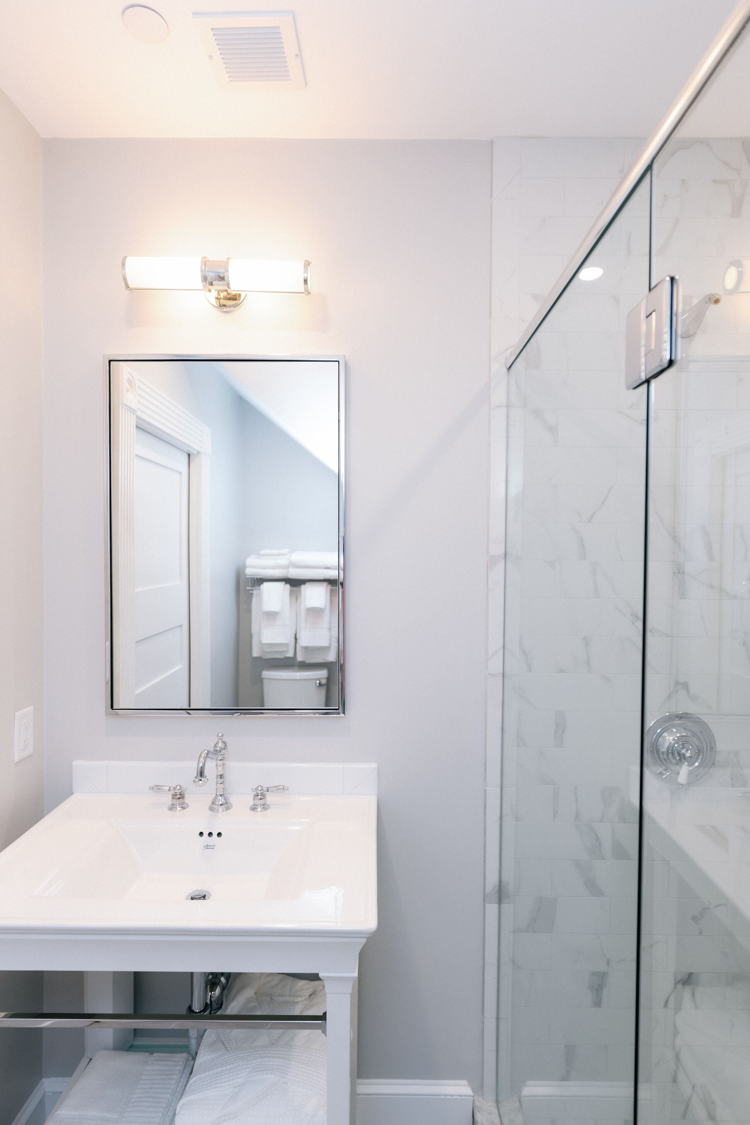 A modern bathroom with a white sink, a large mirror, and a glass shower enclosure.