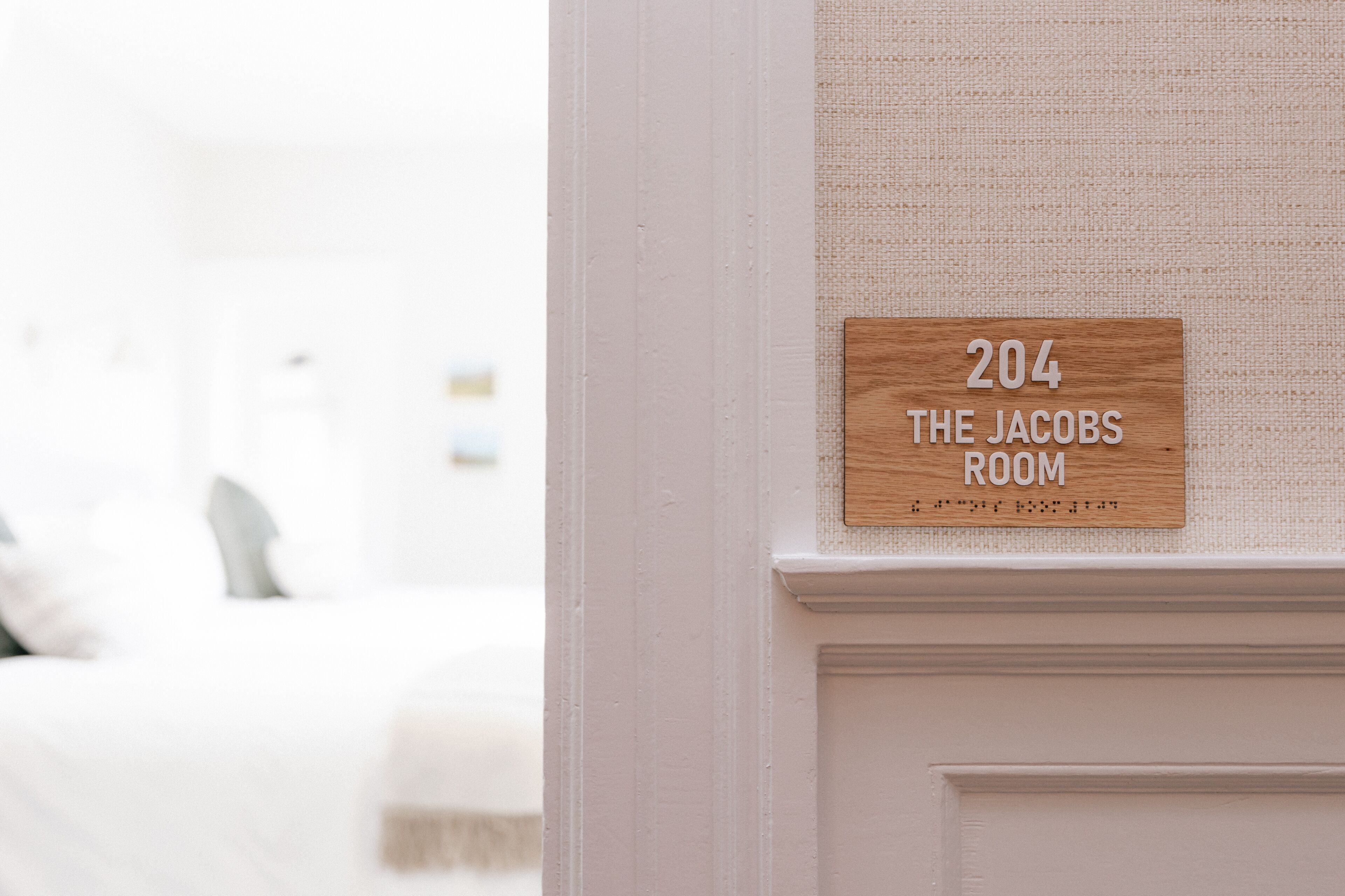Placa na parede indicando o quarto número 204, identificada como 'The Jacobs Room'.