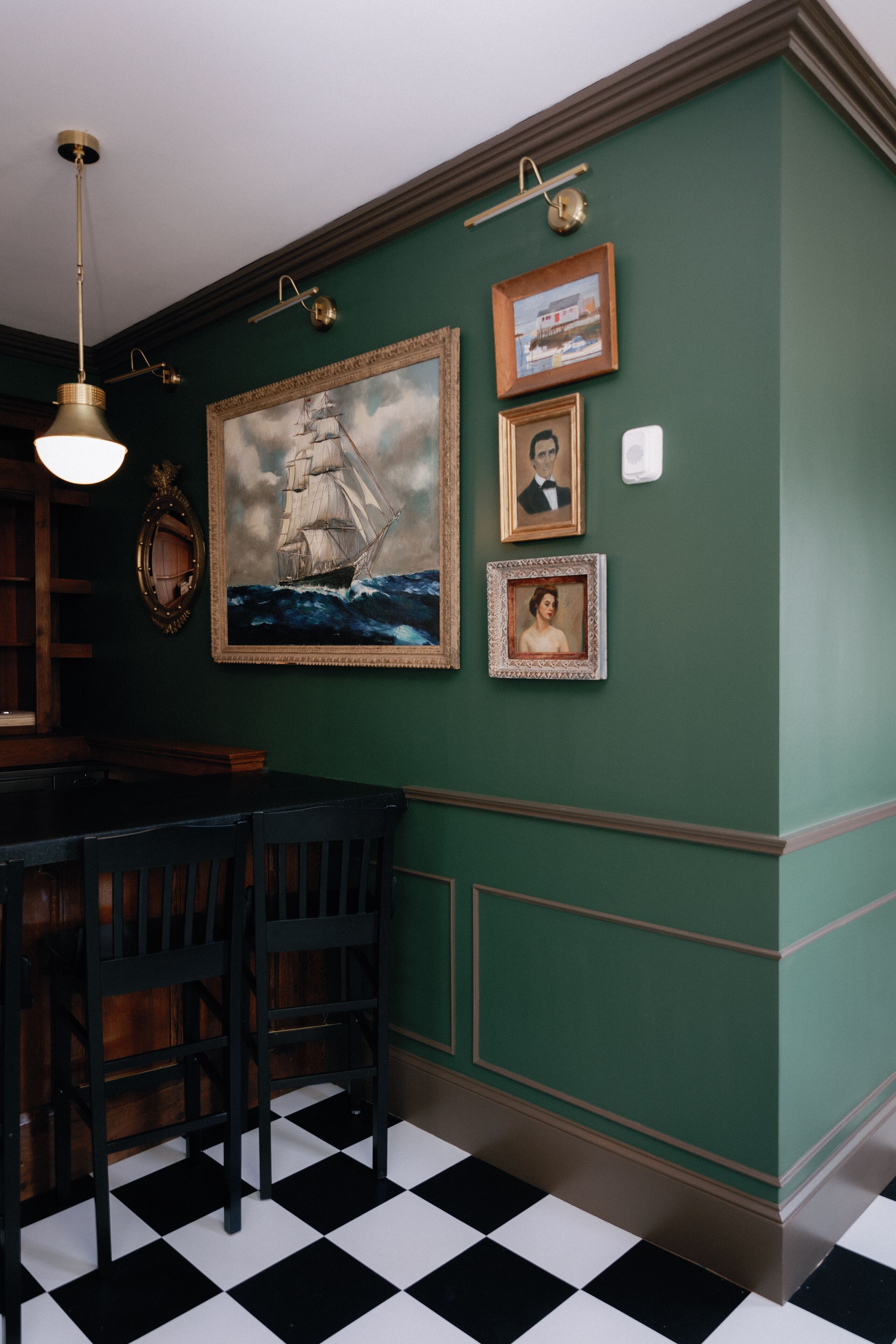 A room with a checkered floor, a dining table with chairs, and framed pictures on the wall.