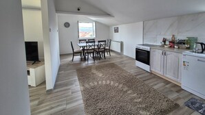 Una cocina moderna con armarios blancos, una estufa y un comedor con mesa y sillas.