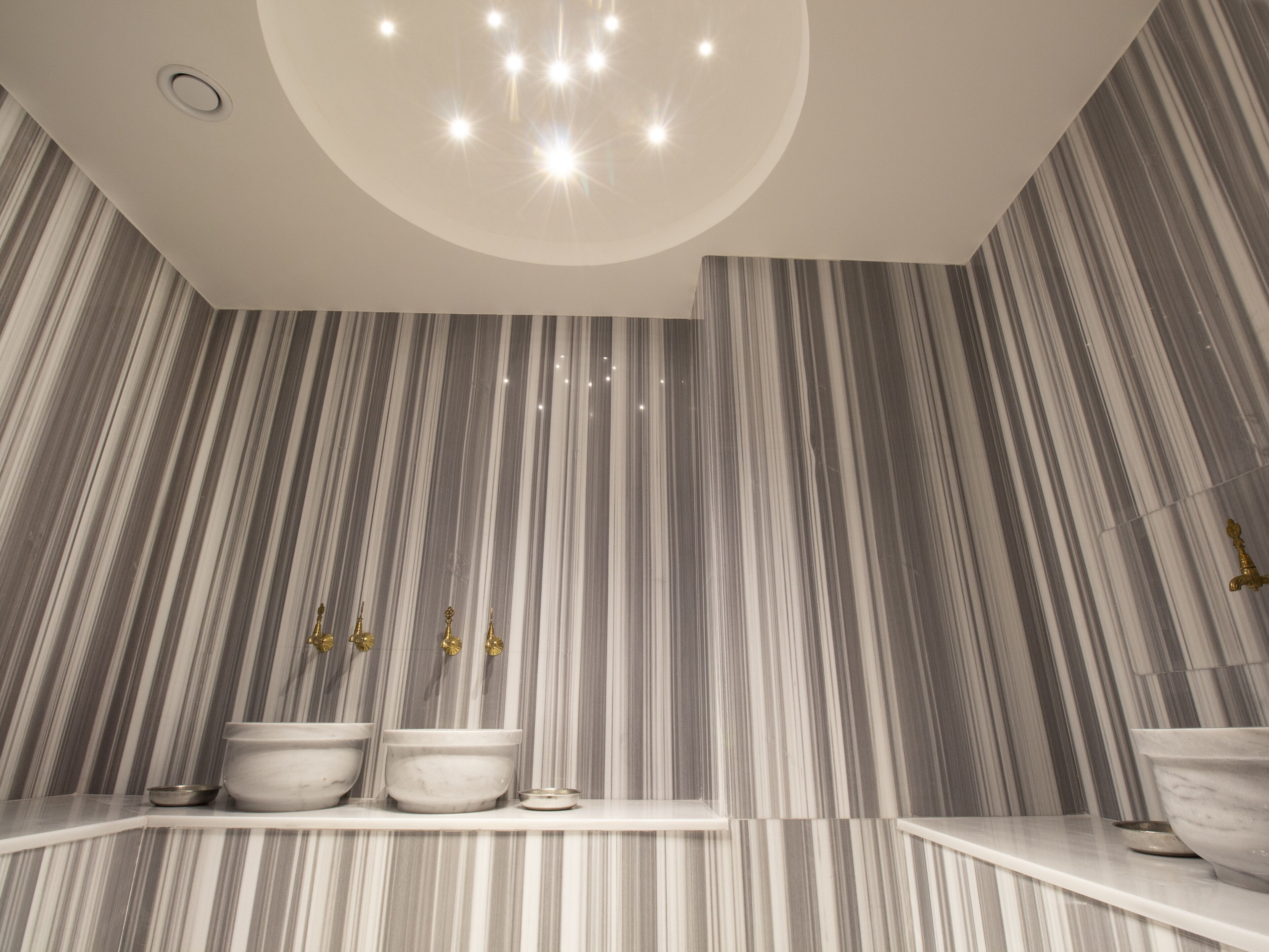 Ein modernes Badezimmer mit Waschtisch aus Marmor, zwei Waschbecken und einem großen Spiegel.