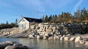 Une propriété située sur la côte, dotée d’un mur en pierre et d’une maison à proximité de l’eau.