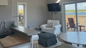 Un vaste espace de vie doté d’un ventilateur de plafond, d’une grande fenêtre, d’un téléviseur à écran plat et offrant une vue sur l’extérieur.