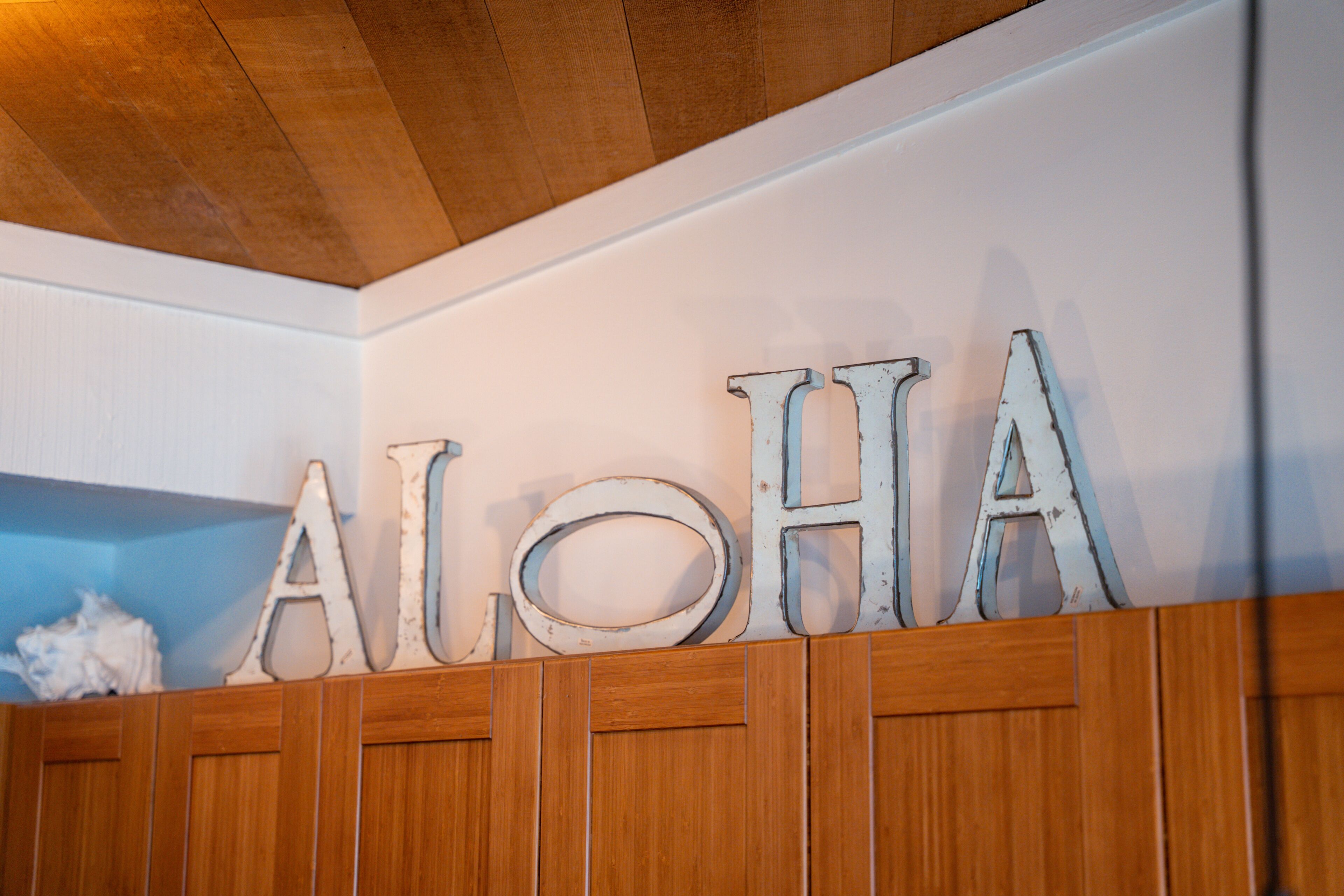 En væg med ordet 'ALOHA' stavet med store, rustikke bogstaver.
