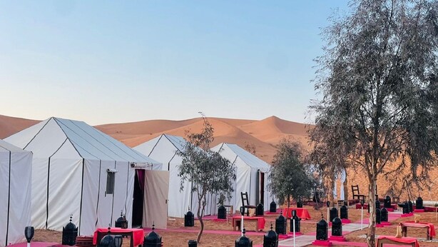 A desert campsite with tents, black lanterns, and red carpets. - Erg Chebbi Dunes Desert Camp (Taouz)