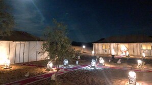 A desert camp with tents, a tree, and illuminated lanterns. - Erg Chebbi Dunes Desert Camp (Taouz)