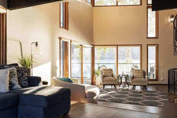 A spacious living area with a large window, a sofa, a coffee table, and two armchairs.