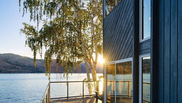 A wooden deck with a glass door leading to a room, overlooking a lake with mountains in the background. - Premier home, Waterfront, Views, Hot Tub, Dogs OK (Lake Chelan)