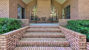 A brick building with a covered patio area featuring steps leading to a table and chairs. - 16th and Golden in Diamondhead (Diamondhead)