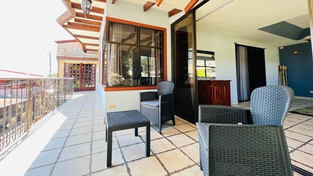 A balcony with wicker furniture, a stone floor, and a view of the surrounding area. - CASA DEL ARBOL ESCAZU (San Antonio)