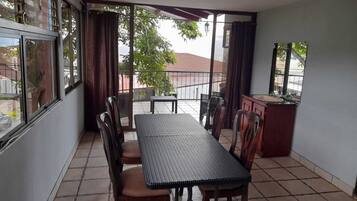 A covered patio area with a table and chairs, a small sink, and a view of the street.