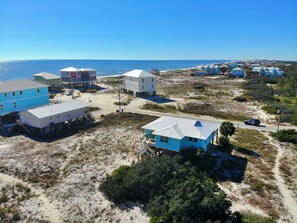 A coastal area with multiple buildings, some elevated on stilts, and a clear view of the ocean.