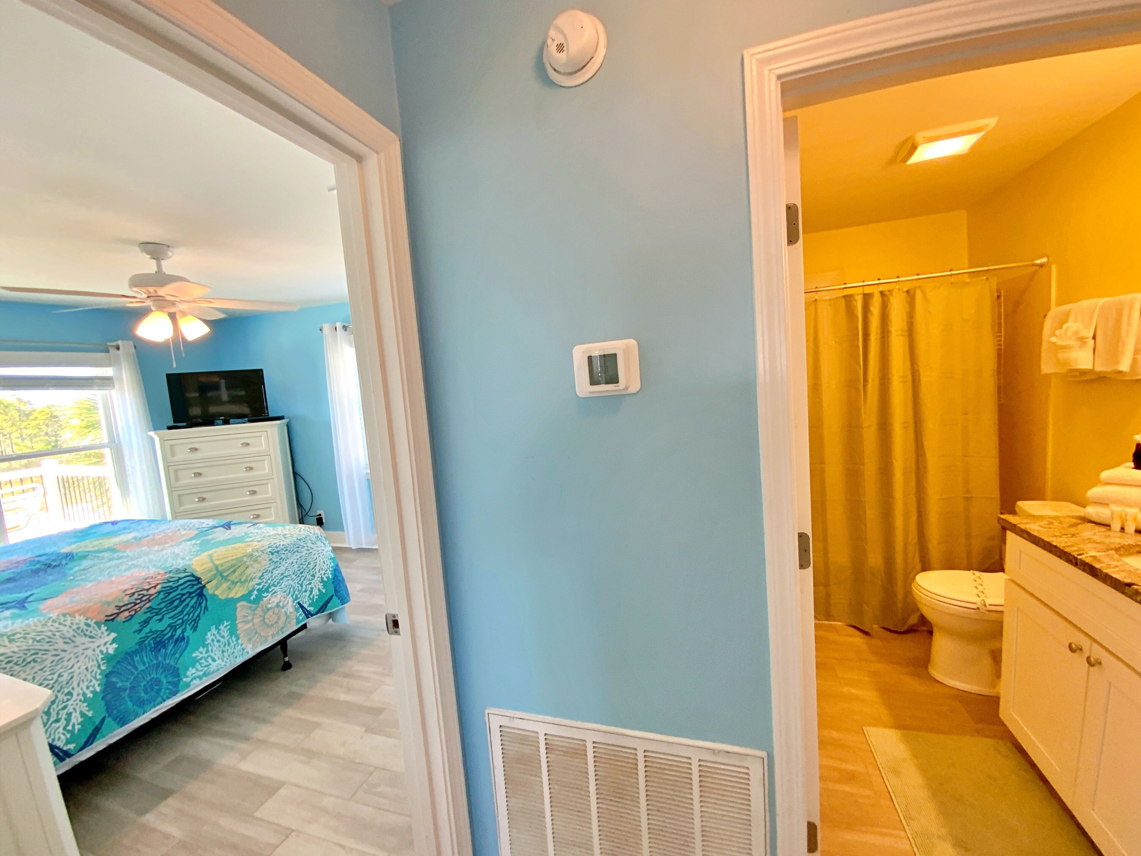 A bedroom with a bed, dresser, and ceiling fan.