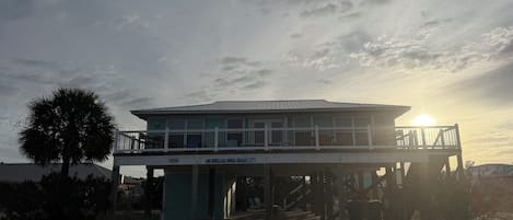 A beachfront building with a balcony and a sign that reads 'A Wave We Go!'.
