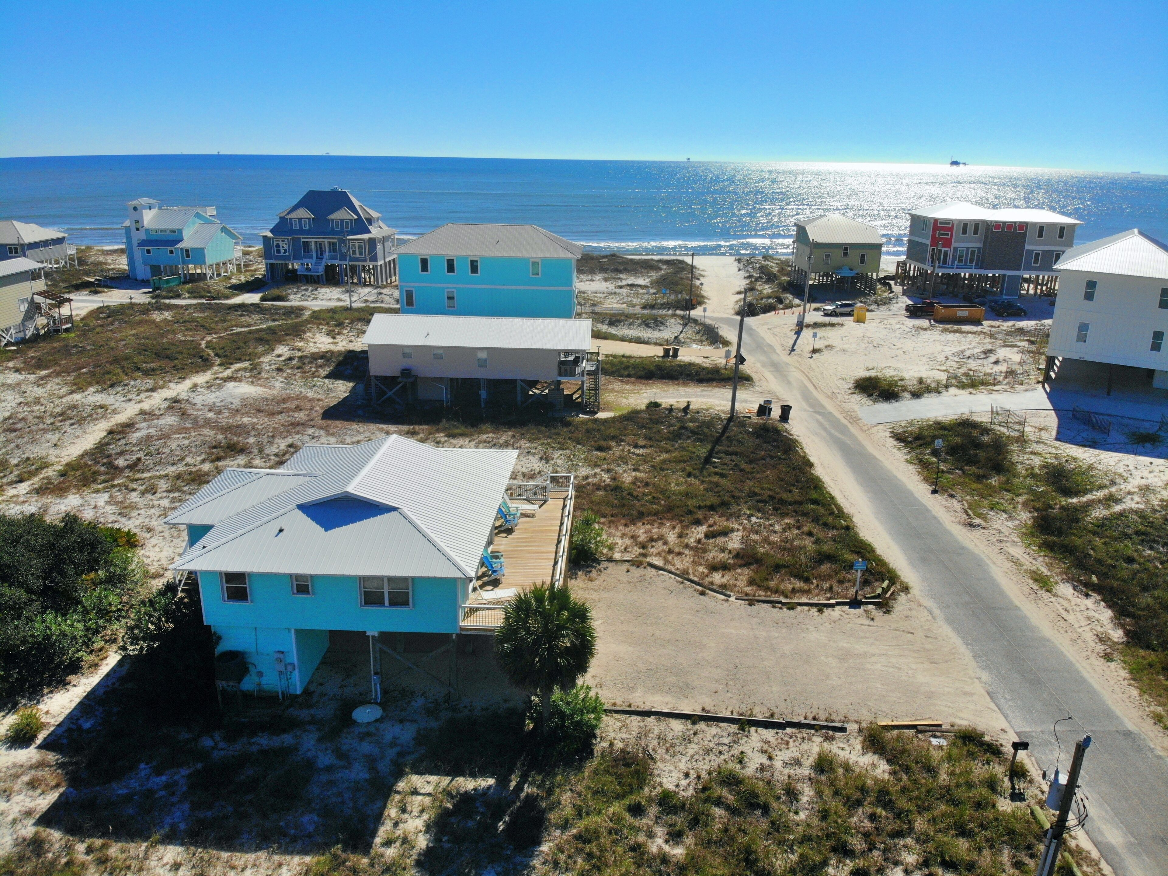 Una zona costiera con diverse case, alcune sollevate su palafitte, e una strada che conduce alla spiaggia.