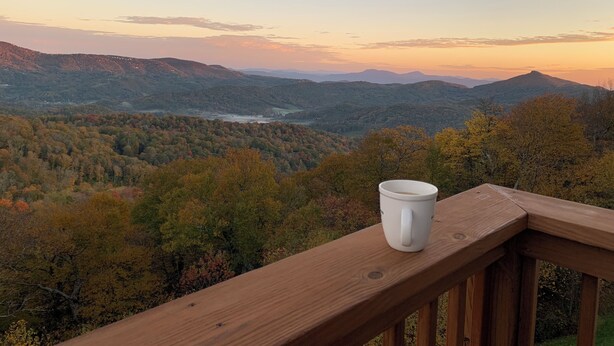 A wooden deck with a white mug, overlooking a mountainous landscape with autumn foliage. - Sugar Ski Premium Loft - Unit 11-703 (Sugar Mountain)
