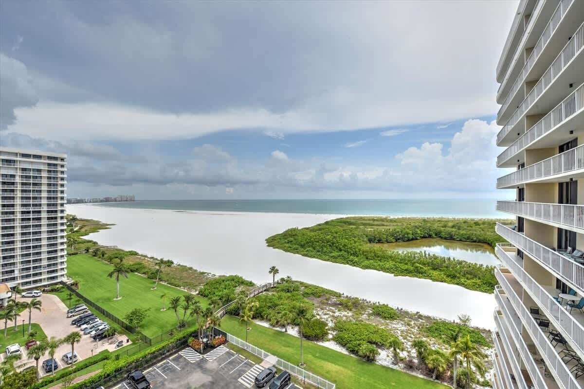 A high-rise hotel overlooking a coastal area with a view of the sea and a mangrove island.