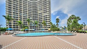 Un hotel grande con fachada curva, piscina y palmeras.